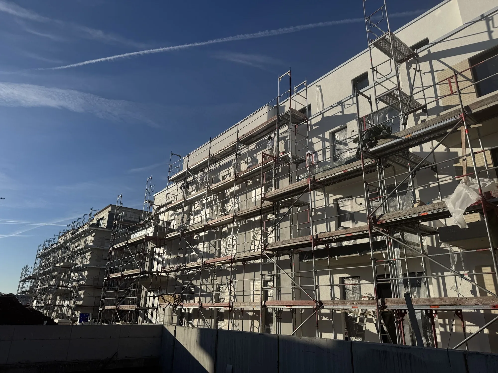 Mehrfamilienhaus im Bau mit Gerüst vor blauem Himmel – Baustelle von Loga-Bau