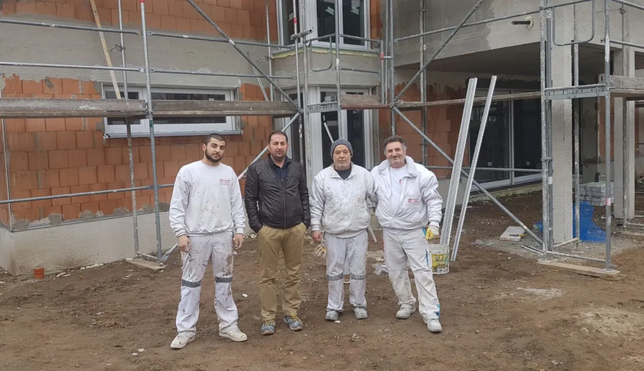 Vier Mitarbeiter von Loga-Bau vor einem eingerüsteten Neubau mit Ziegelmauerwerk
