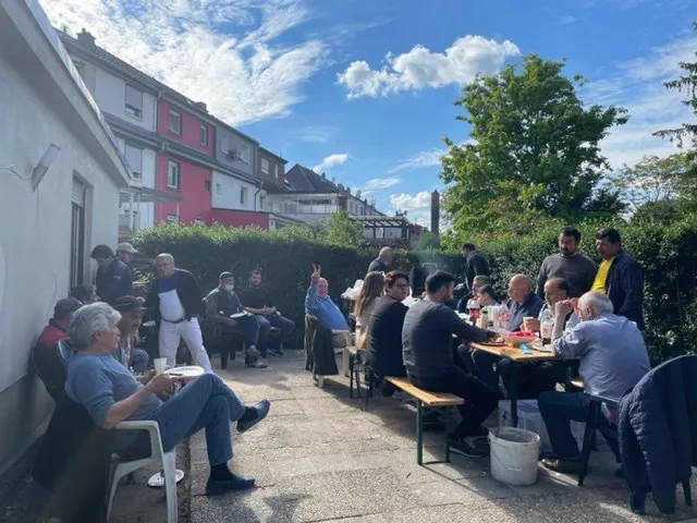 Mitarbeitende von Loga-Bau sitzen bei einem Sommerfest an Biertischen im Freien